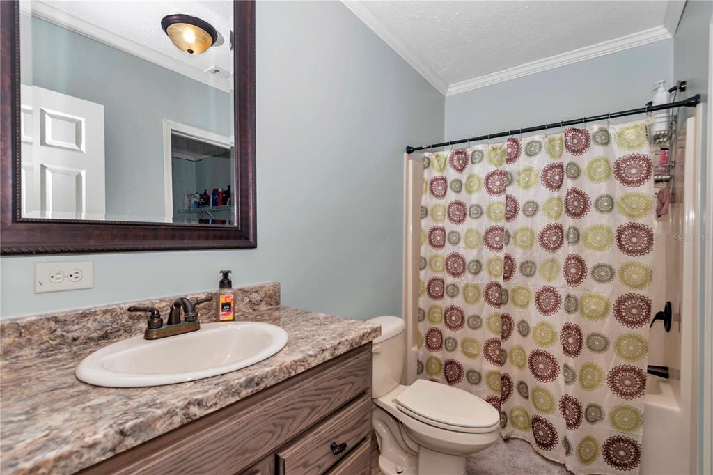 7565 Dewey Robbins Road Howey-in-the-Hills, FL 34737 - Photo 20 of 42 a bathroom with a granite countertop sink a toilet a mirror and shower curtain