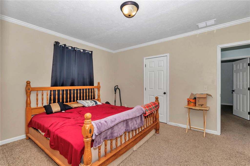 7565 Dewey Robbins Road Howey-in-the-Hills, FL 34737 - Photo 21 of 42 a bed room with a bed and a chair