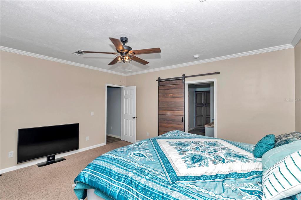 7565 Dewey Robbins Road Howey-in-the-Hills, FL 34737 - Photo 30 of 42 a bedroom with a bed and a flat screen tv