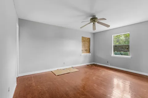 an empty room with windows and fan