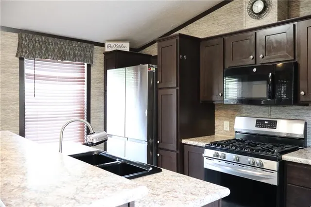 a kitchen with stainless steel appliances kitchen island granite countertop a sink stove and refrigerator