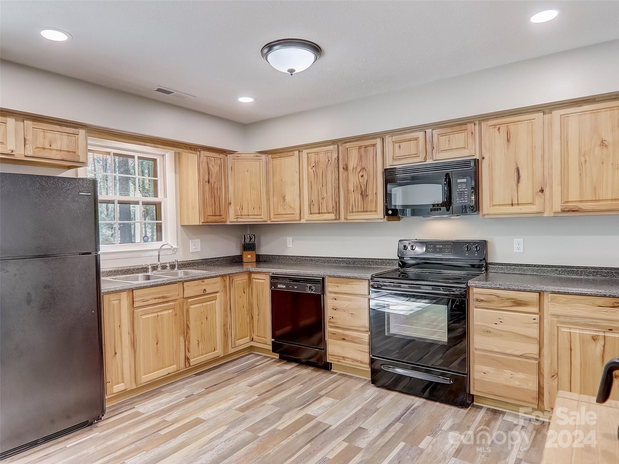 1191 Dupont Road Hendersonville, NC 28739 - Photo 9 of 48 a kitchen with stainless steel appliances granite countertop a stove top oven a sink dishwasher and a refrigerator with wooden cabinets