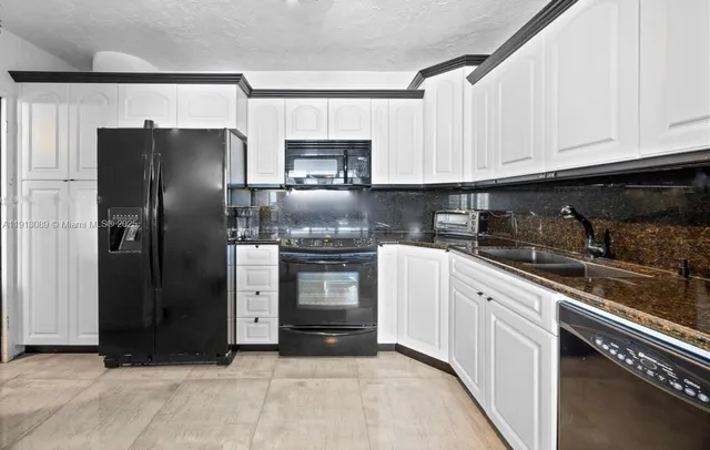 a kitchen with stainless steel appliances granite countertop a refrigerator a stove and a sink