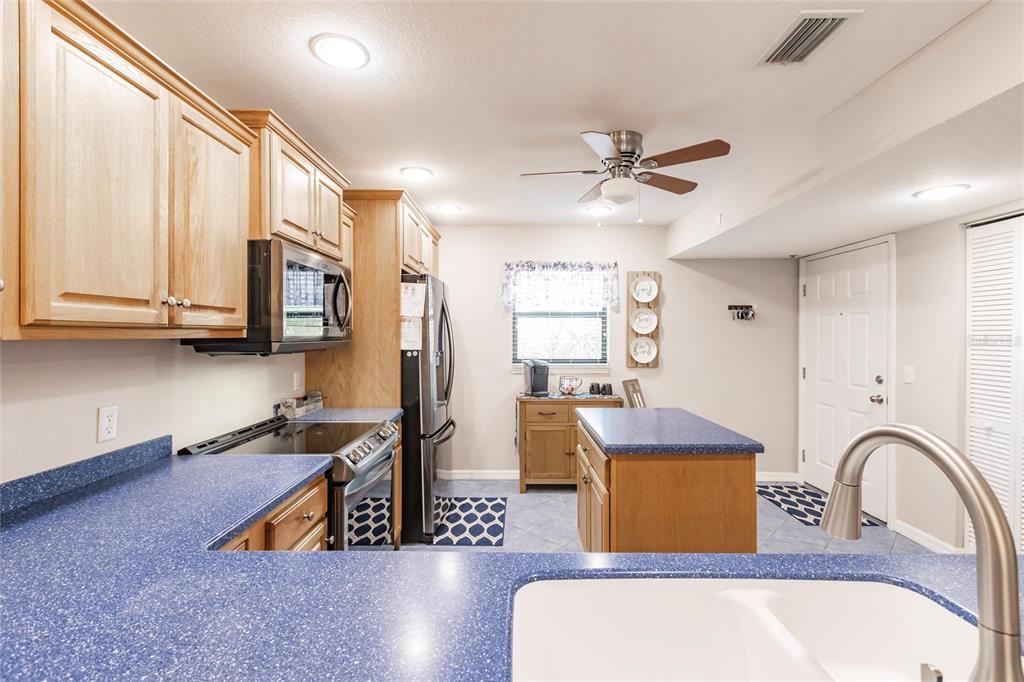 175 Kings Highway, Unit 538 Punta Gorda, FL 33983 - Photo 13 of 46 a living room with stainless steel appliances kitchen island granite countertop a stove a sink dishwasher and white countertops with wooden floor