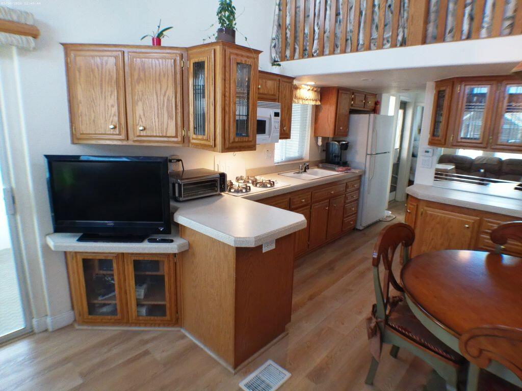 84136 Ave 44, Unit 582 Indio, CA 92203 - Photo 29 of 56 a kitchen with kitchen island granite countertop wooden cabinets dining table and chairs