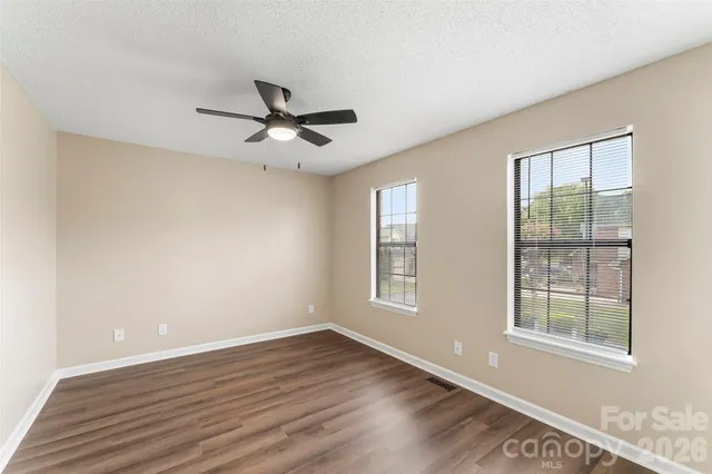 a view of empty room with wooden floor and fan