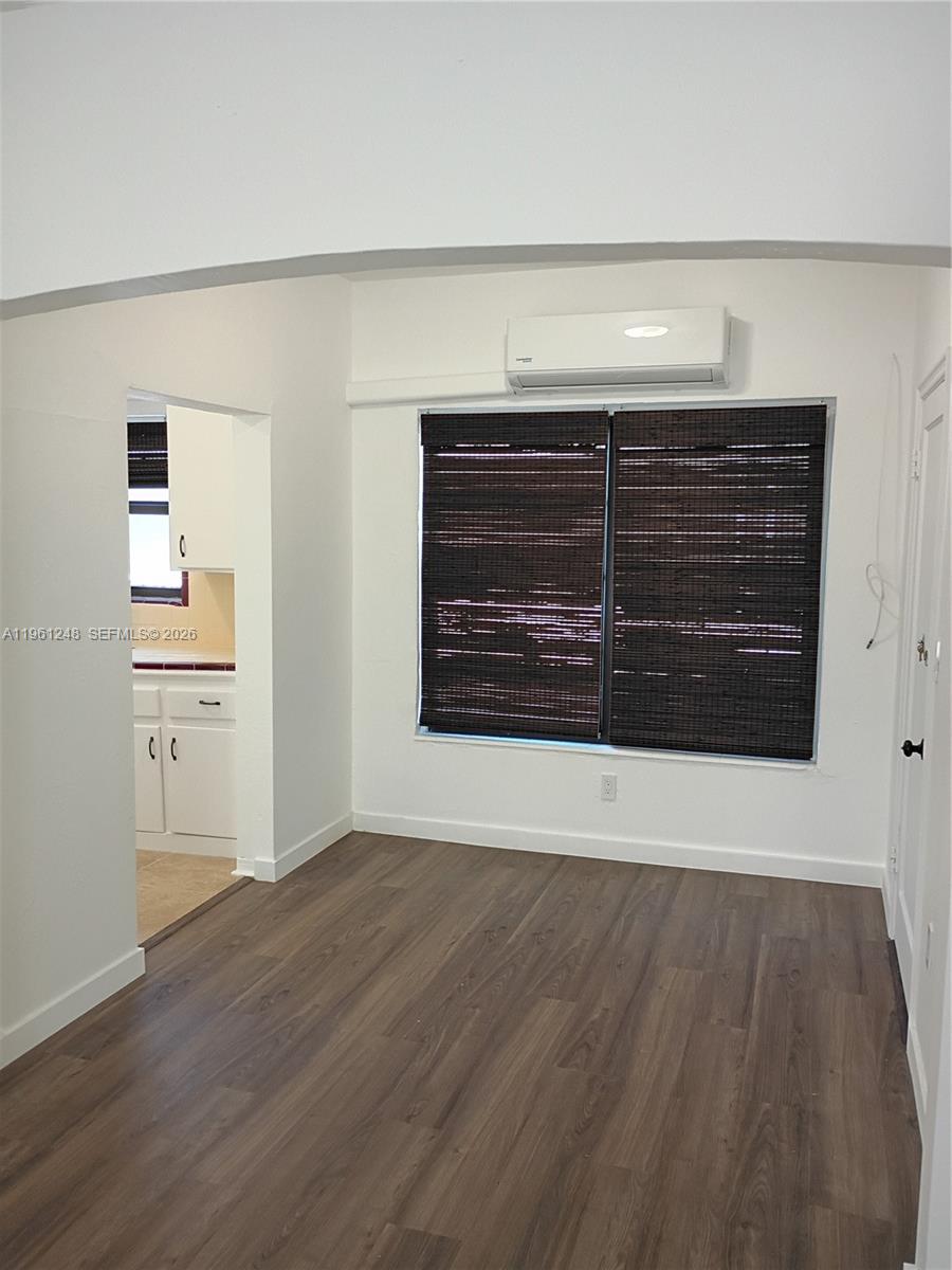 235 83rd Street, Unit 3 Miami Beach, FL 33141 - Photo 6 of 27 a view of an empty room with wooden floor and a window