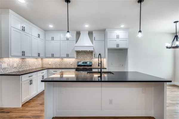 a kitchen with stainless steel appliances granite countertop a sink a stove and a refrigerator