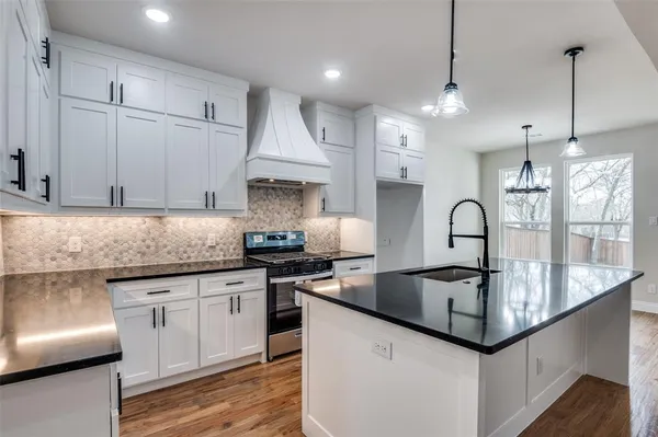 a kitchen with granite countertop a sink a stove and cabinets