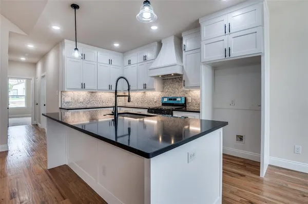 a kitchen with stainless steel appliances granite countertop a sink a stove and a wooden floors
