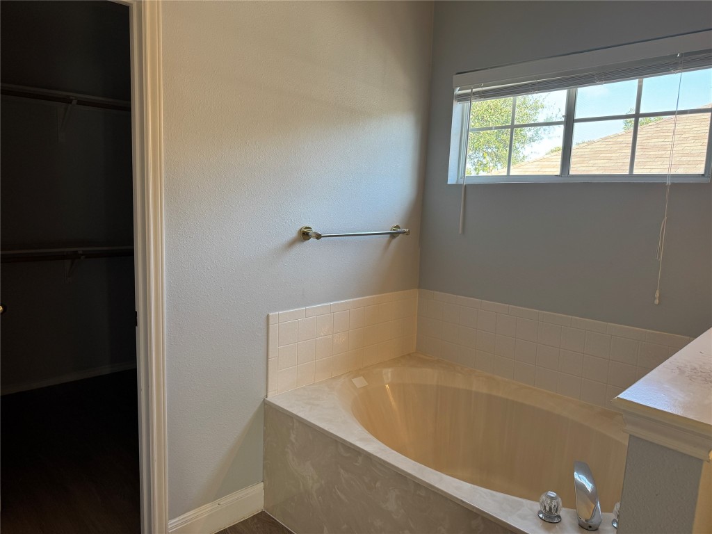 12714 Tantara Drive Austin, TX 78729 - Photo 15 of 25 Full bath with a spacious closet, a bath, vanity, and a textured wall