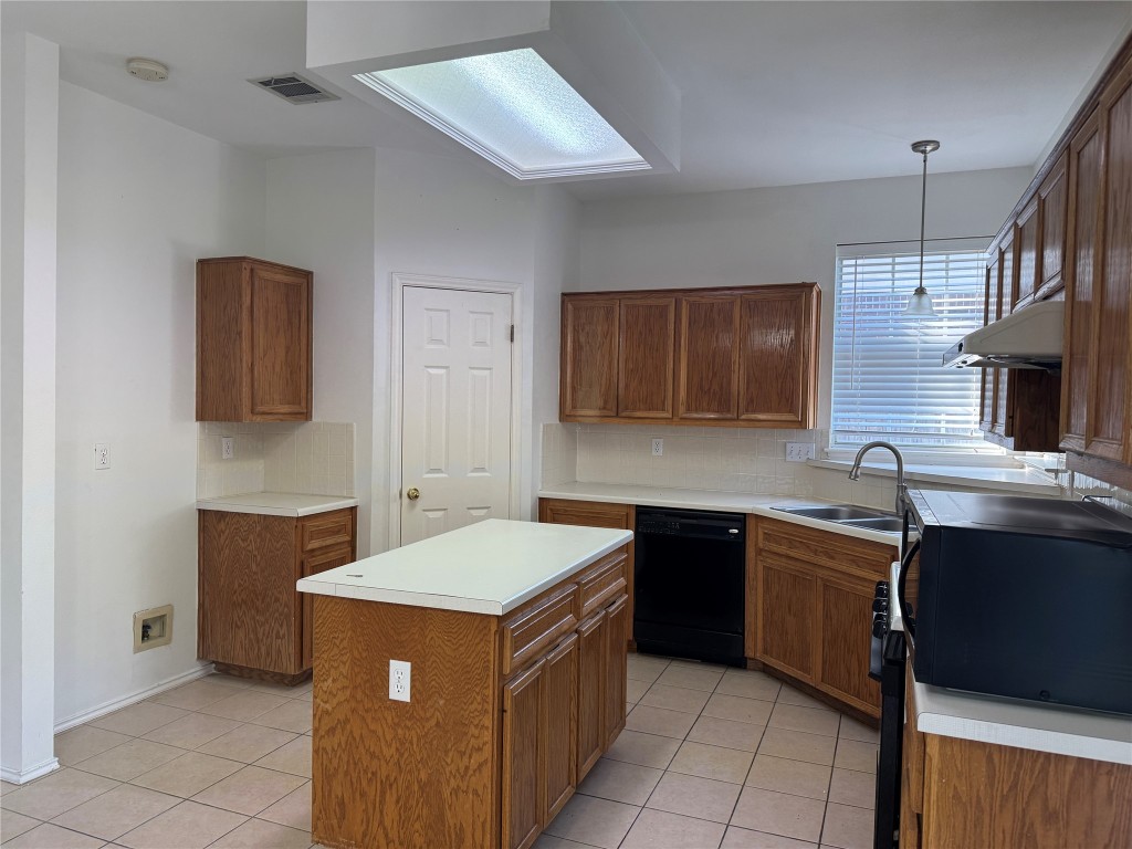 12714 Tantara Drive Austin, TX 78729 - Photo 24 of 25 Kitchen with black appliances, brown cabinetry, and light countertops