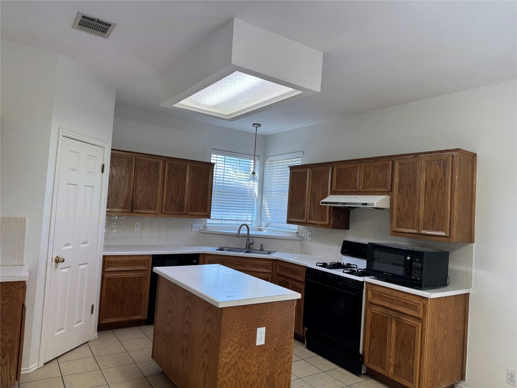 12714 Tantara Drive Austin, TX 78729 - Photo 8 of 25 Kitchen with light countertops, decorative backsplash, black appliances, and light tile patterned floors