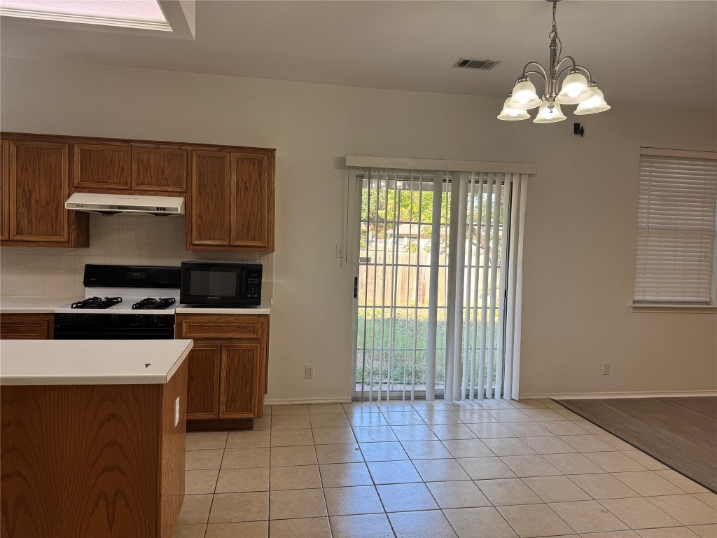 12714 Tantara Drive Austin, TX 78729 - Photo 10 of 25 Kitchen with light countertops, light tile patterned flooring, brown cabinetry, pendant lighting, and gas stove