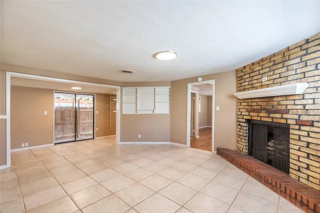 a view of an empty room with a fireplace and a window