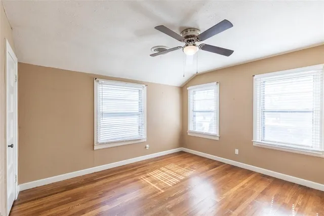 a view of an empty room with wooden floor and window
