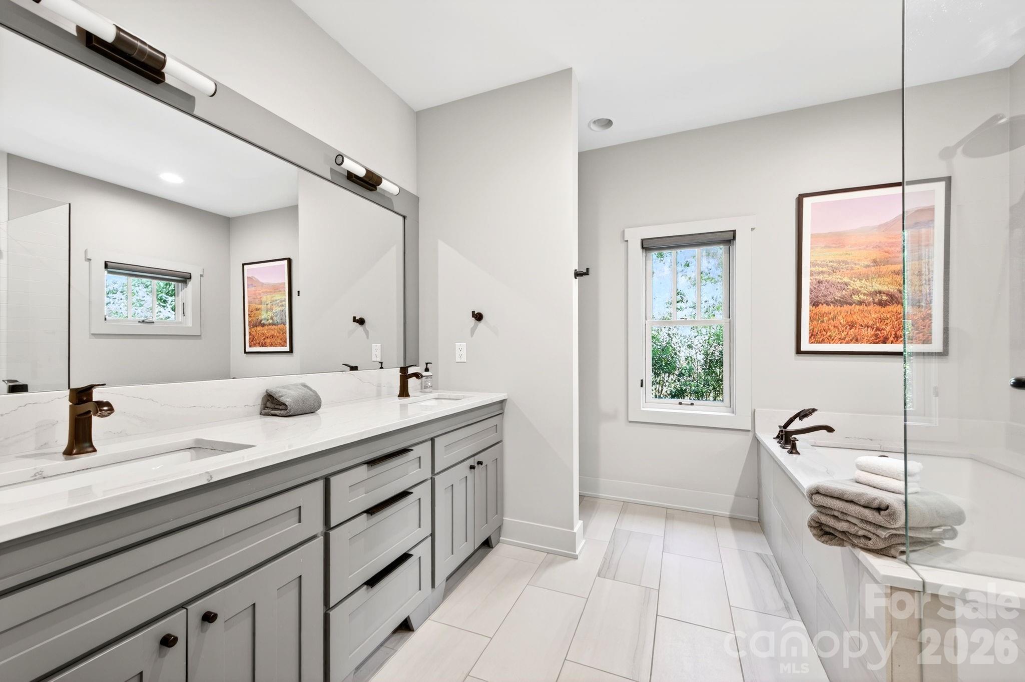 235 Bull Creek Road Asheville, NC 28805 - Photo 15 of 47 a spacious bathroom with a double vanity sink a mirror and a bathtub