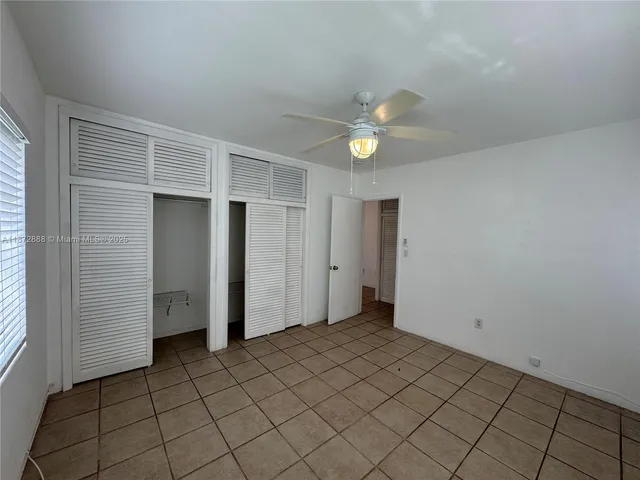 an empty room with closet and ceiling fan