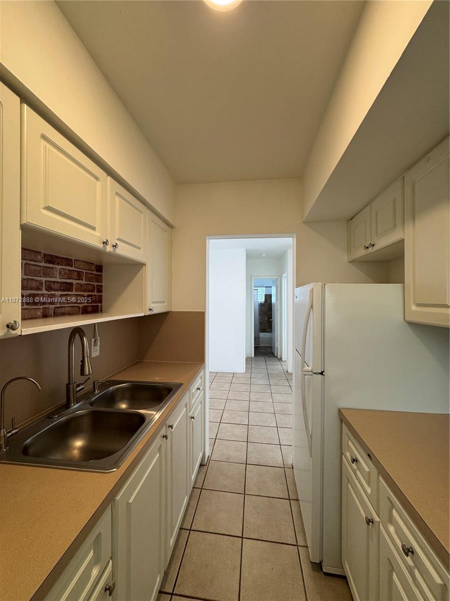 921 Meridian Avenue, Unit 7 Miami Beach, FL 33139 - Photo 5 of 31 a kitchen with a sink a refrigerator and cabinets