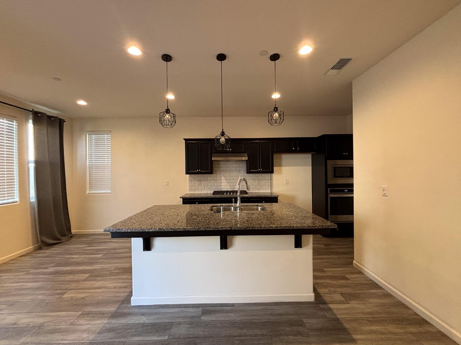827 Fir Street West Madera, CA 93636 - Photo 14 of 63 a kitchen with kitchen island stainless steel appliances sink cabinets and wooden floor
