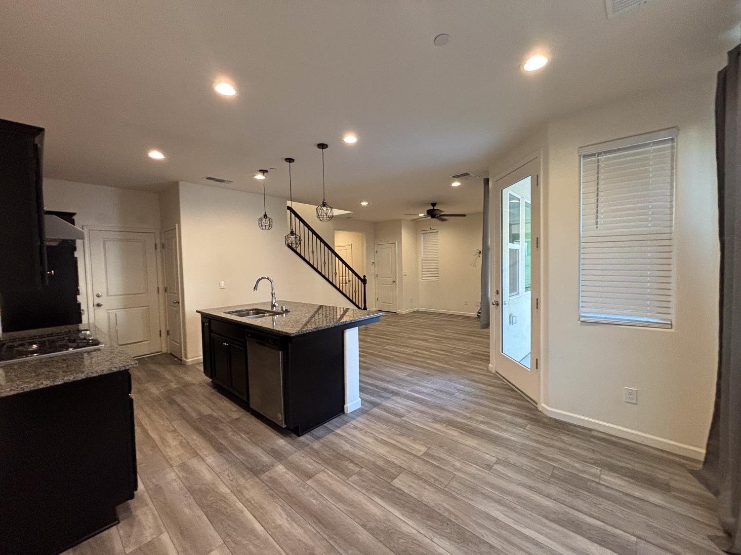 827 Fir Street West Madera, CA 93636 - Photo 10 of 63 a kitchen with stainless steel appliances kitchen island wooden floors granite counter tops and a view of living room