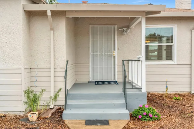 a front view of a house with a potted plant and floor to ceiling window