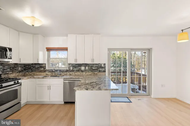 a kitchen with granite countertop white cabinets stainless steel appliances a sink and a window