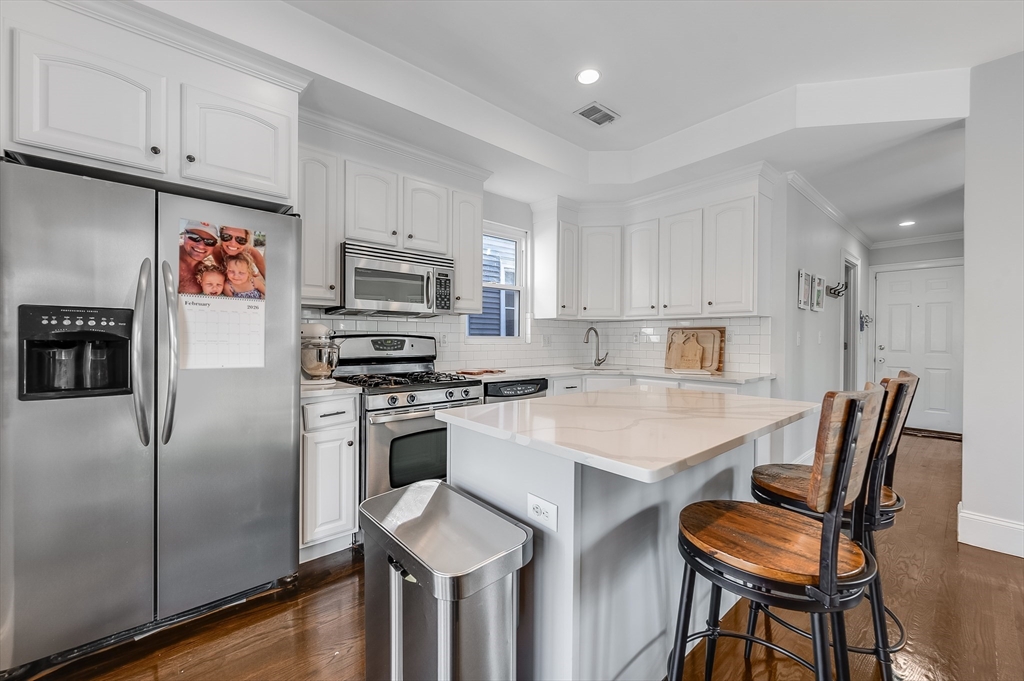 720 East 8th Street, Unit 2 Boston, MA 02127 - Photo 3 of 14 a kitchen with stainless steel appliances granite countertop a stove a refrigerator a white table and chairs