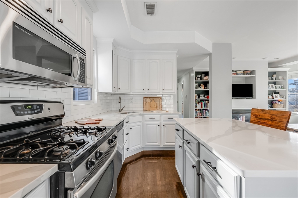720 East 8th Street, Unit 2 Boston, MA 02127 - Photo 5 of 14 a kitchen with stainless steel appliances a sink dishwasher stove and oven with wooden floor