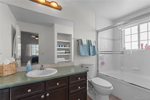 a bathroom with a granite countertop sink toilet mirror and shower