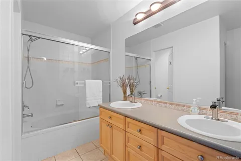 a bathroom with a granite countertop sink a mirror a bathtub and shower