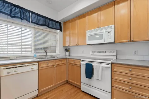 a kitchen with granite countertop white cabinets and white appliances