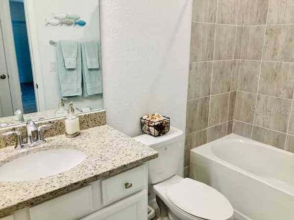 a bathroom with a granite countertop toilet a sink and bathtub