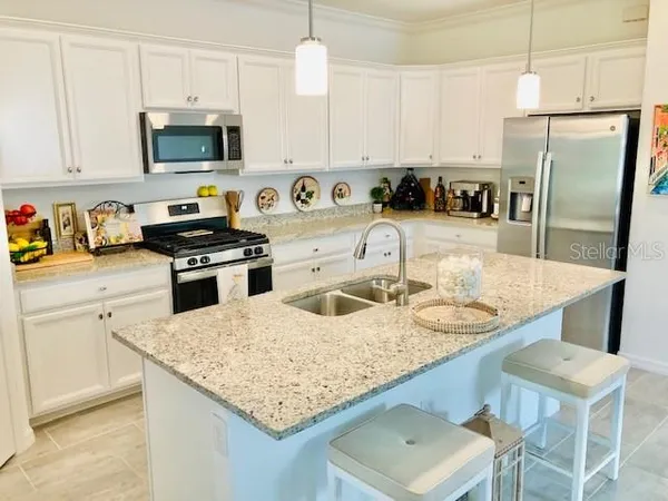 a kitchen with stainless steel appliances granite countertop a sink a stove and a refrigerator