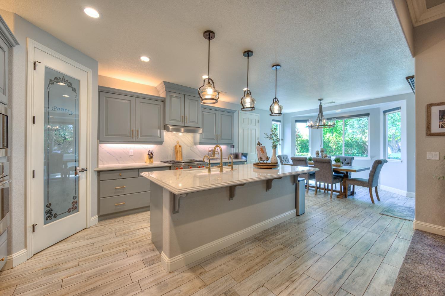 3731 Serena Avenue Clovis, CA 93619 - Photo 13 of 54 a kitchen with a sink a counter space dining table and chairs