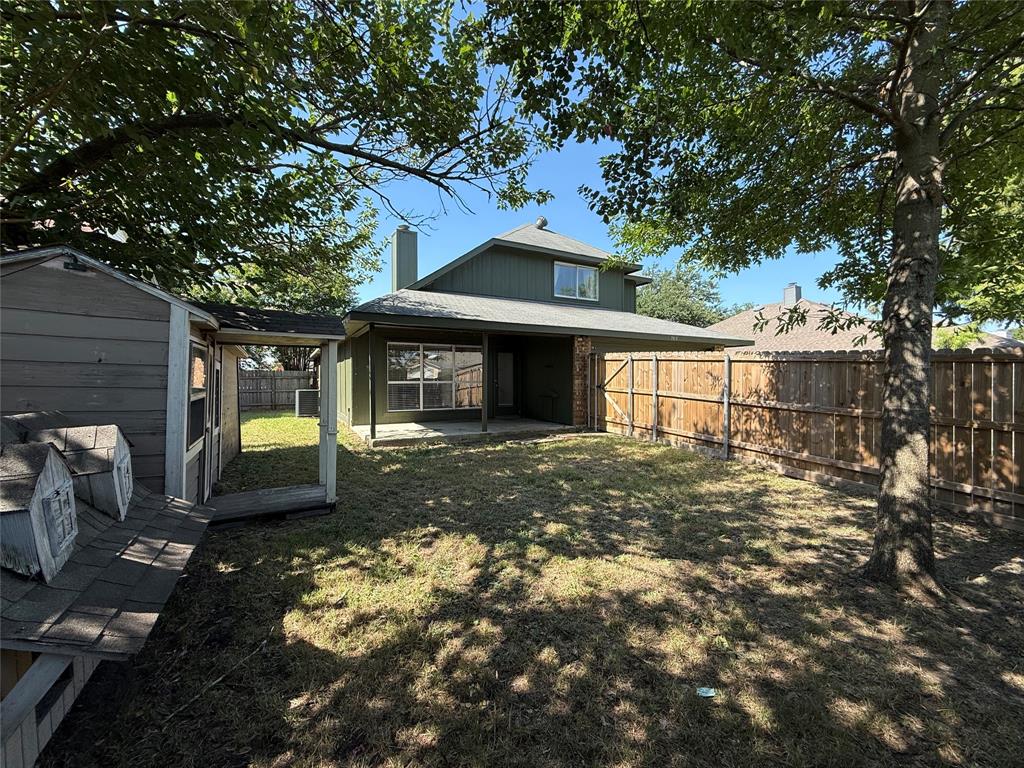 7913 Rice Drive Rowlett, TX 75088 - Photo 24 of 25 Spacious backyard featuring a large tree, shed structure, wood privacy fencing, and a covered patio area with a brick column accent