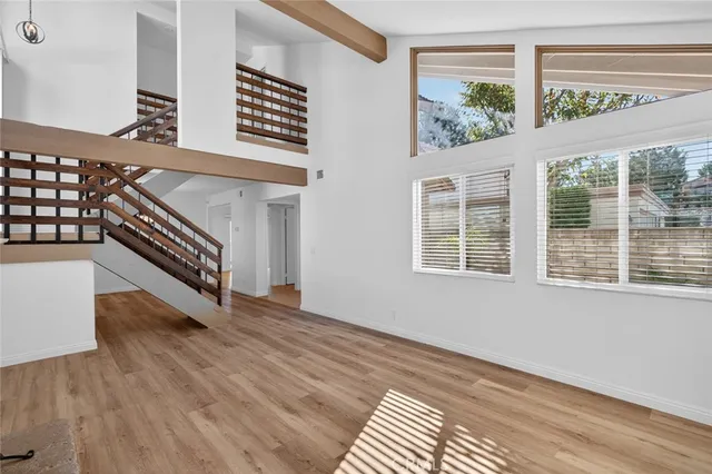 a view of an empty room with wooden floor and stairs