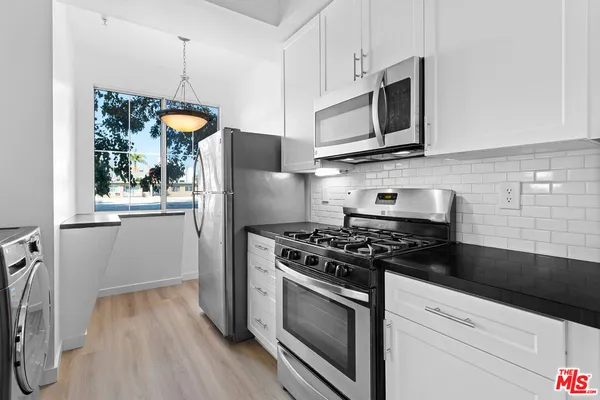 a kitchen with stainless steel appliances granite countertop a stove a refrigerator and a microwave