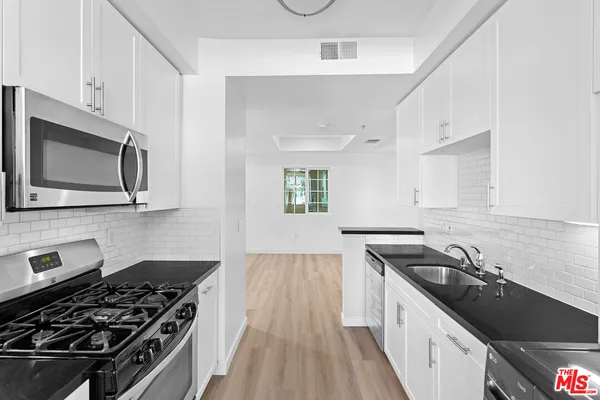 a kitchen with stainless steel appliances a sink stove and cabinets