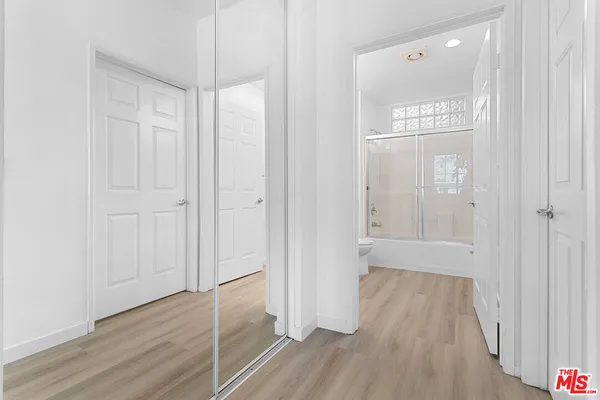 a view of an empty room with wooden floor and a bathroom