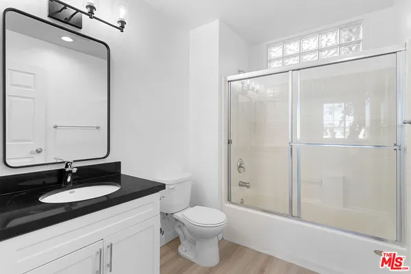 a bathroom with a sink a toilet and shower a mirror