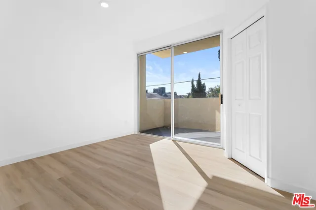 a view of a hallway with wooden floor and a bathroom