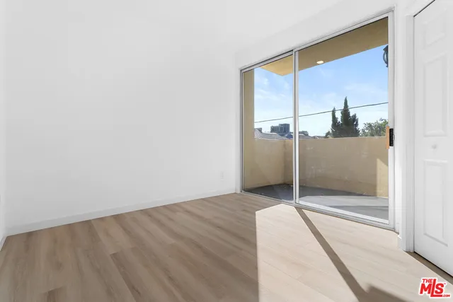 a view of a hallway with wooden floor and a bathroom