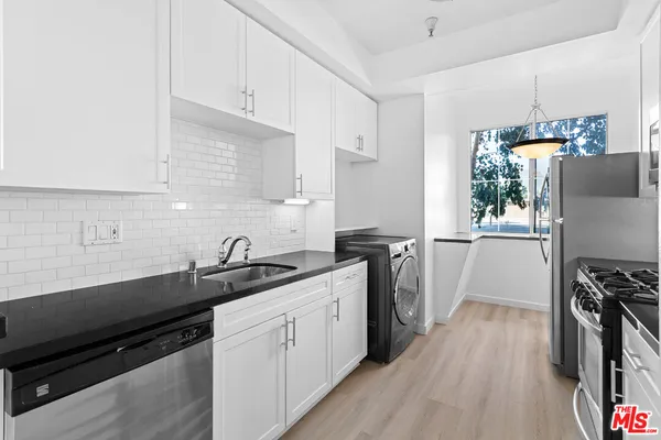 a kitchen with a sink appliances cabinets and a counter top space