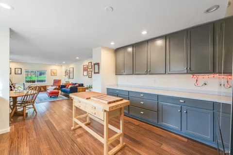 a view of a kitchen with kitchen island granite countertop lots of wooden cabinets a sink dishwasher and a stove with wooden floor