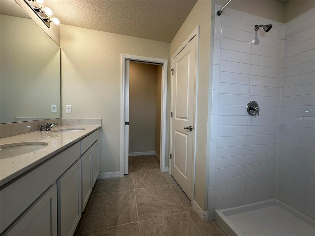 4806 Sparkling Shell Avenue Kissimmee, FL 34746 - Photo 12 of 19 a bathroom with a granite countertop sink a mirror and a bathtub