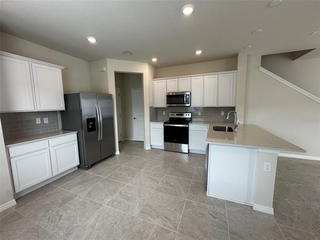 4806 Sparkling Shell Avenue Kissimmee, FL 34746 - Photo 7 of 19 a kitchen with stainless steel appliances a refrigerator sink microwave and cabinets