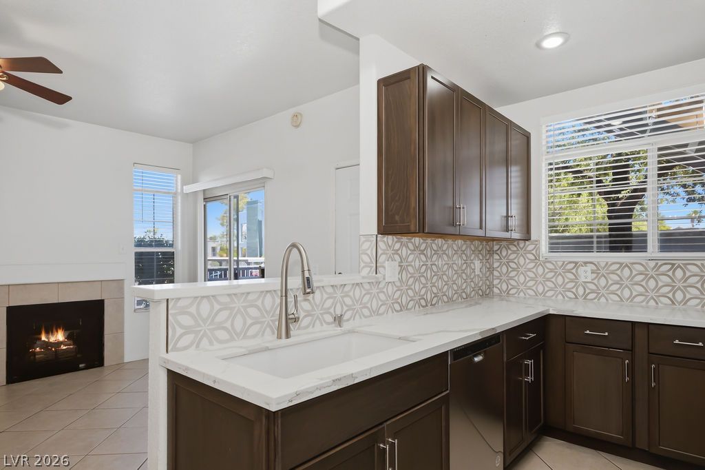 2201 Ramsgate Drive, Unit 514 Henderson, NV 89074 - Photo 11 of 28 A contemporary kitchen features sleek countertops and rich cabinetry, complemented by a cozy fireplace in the adjacent living area.