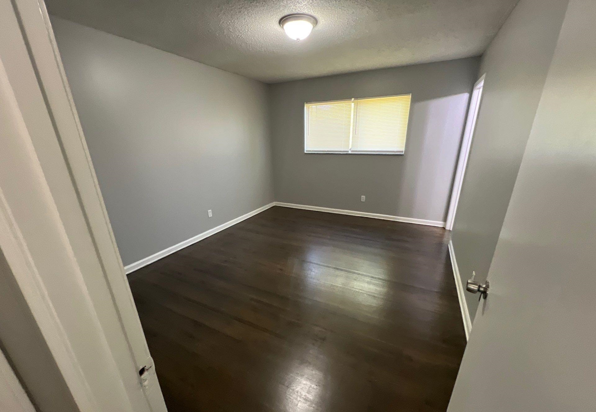 4936 Warrington Road Memphis, TN 38118 - Photo 9 of 13 an empty room with wooden floor and windows