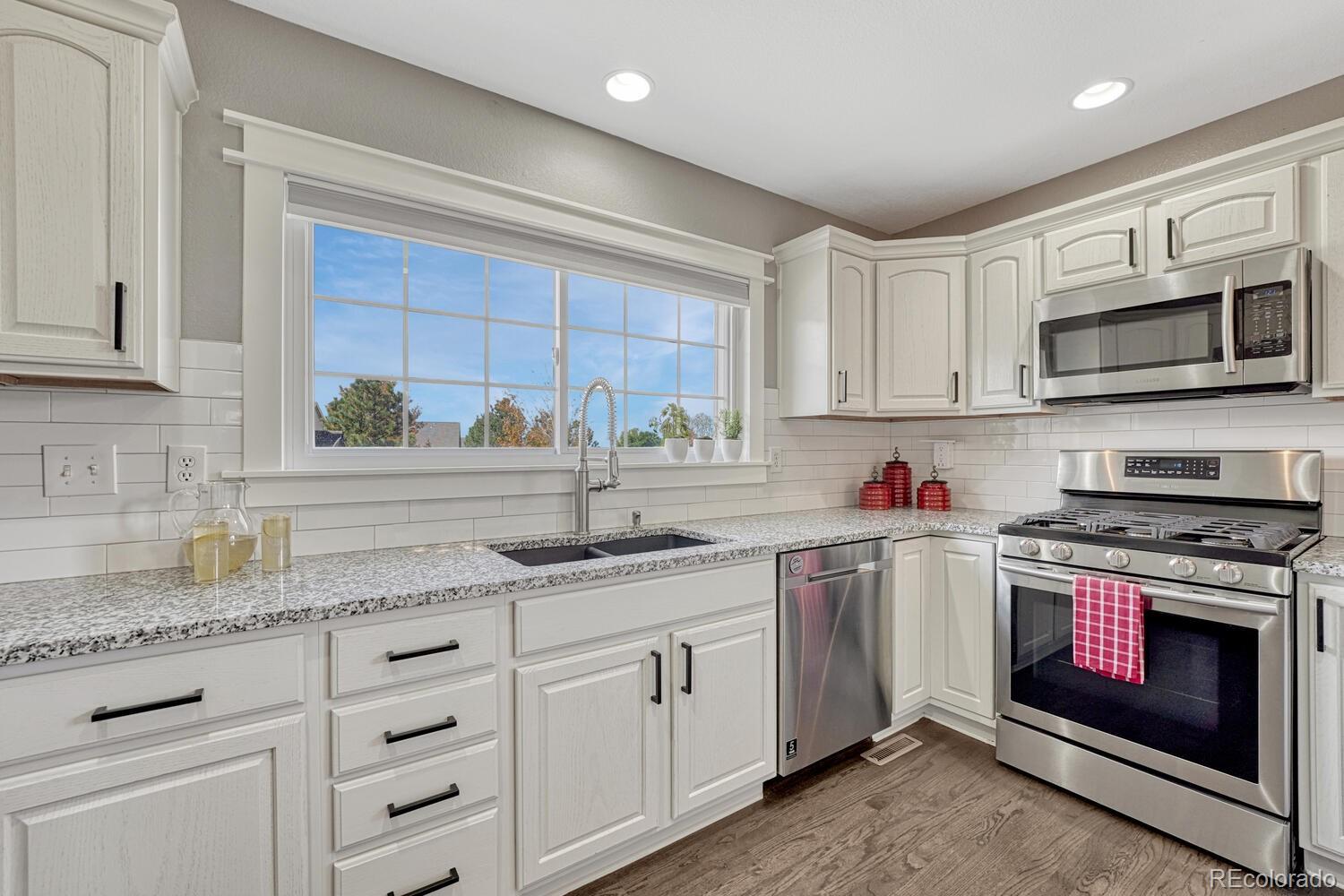 6335 Trailhead Road Highlands Ranch, CO 80130 - Photo 11 of 50 a kitchen with granite countertop white cabinets white stainless steel appliances and a sink